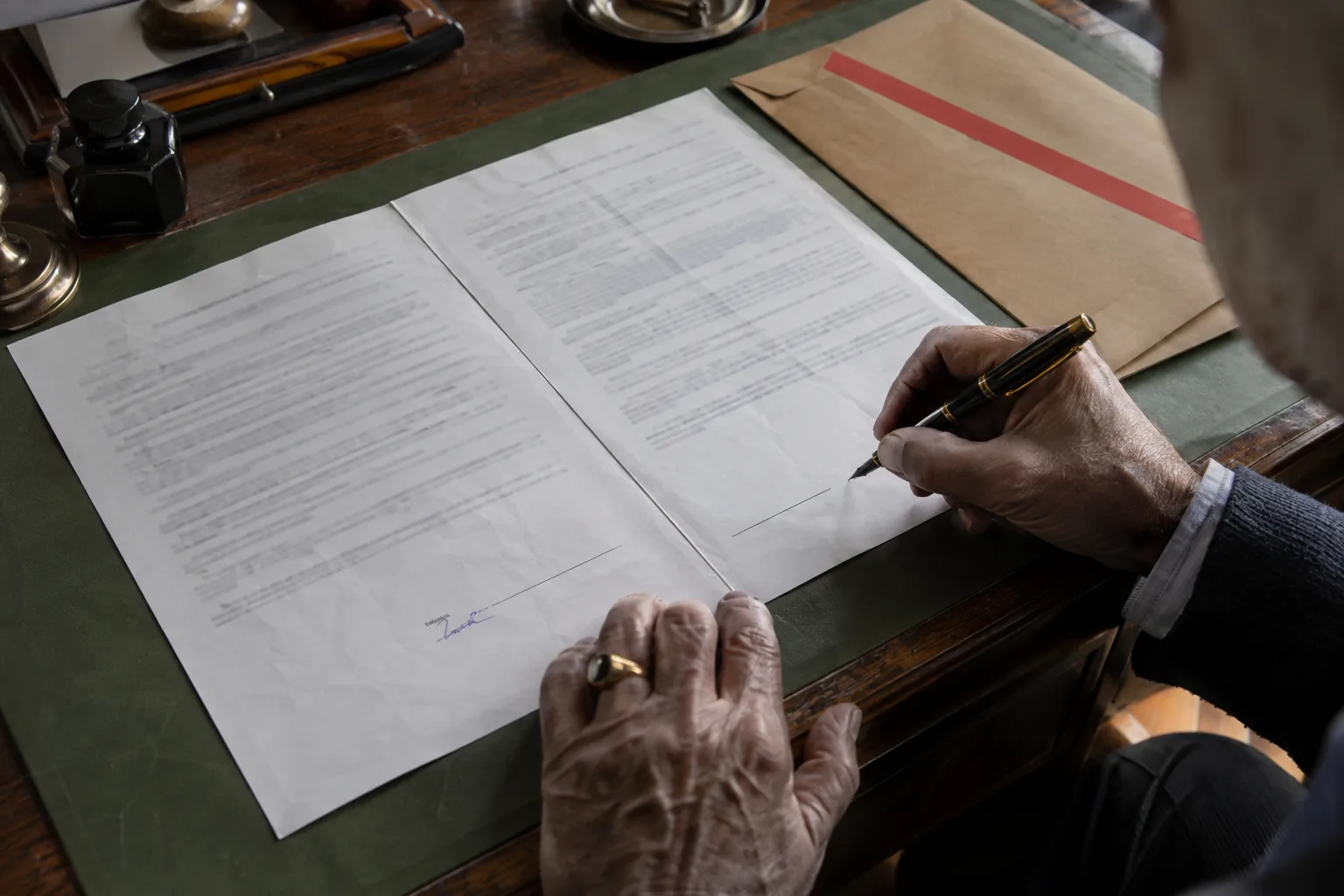 Partner signing a mutual NDA with a fountain pen before the confidential brief is opened