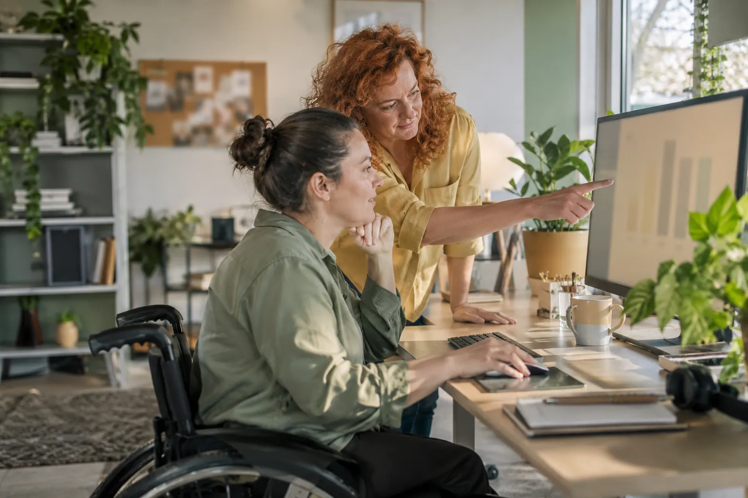 Two colleagues reading a traffic chart together on an office monitor