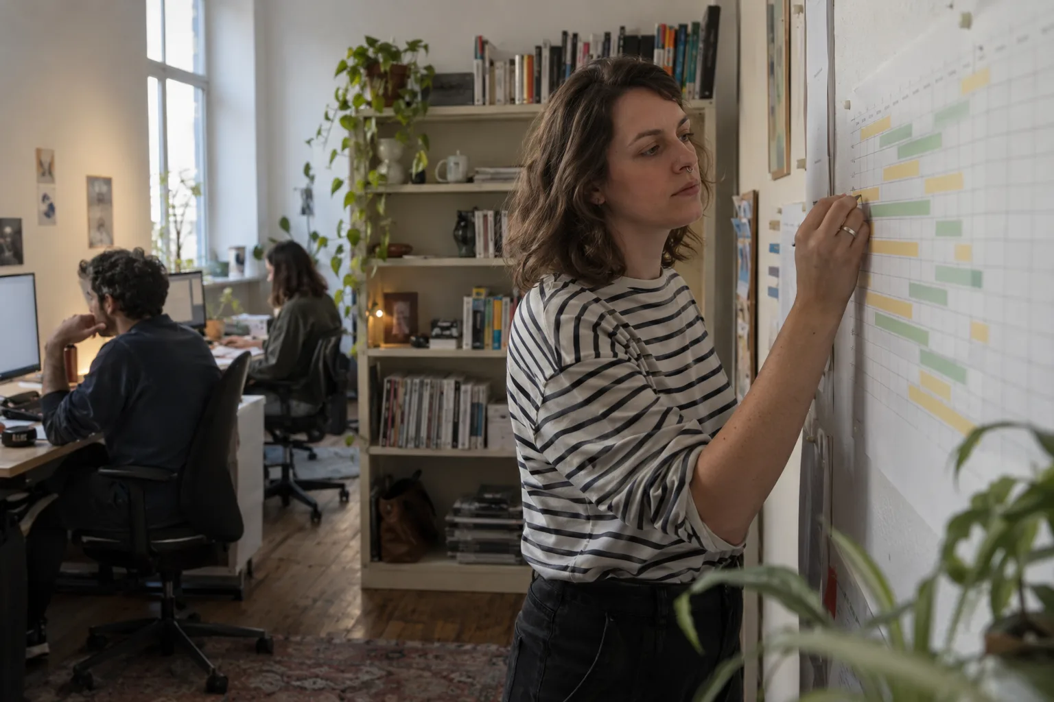 Boutique PR agency owner updating a staff rota on the wall of a small office